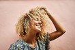© Александра Белинская - portrait of an attractive blonde female smiling and touching her hair curly hair in pink wall background