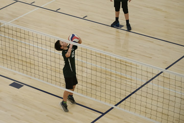 Volleyball player setting the ball by the net