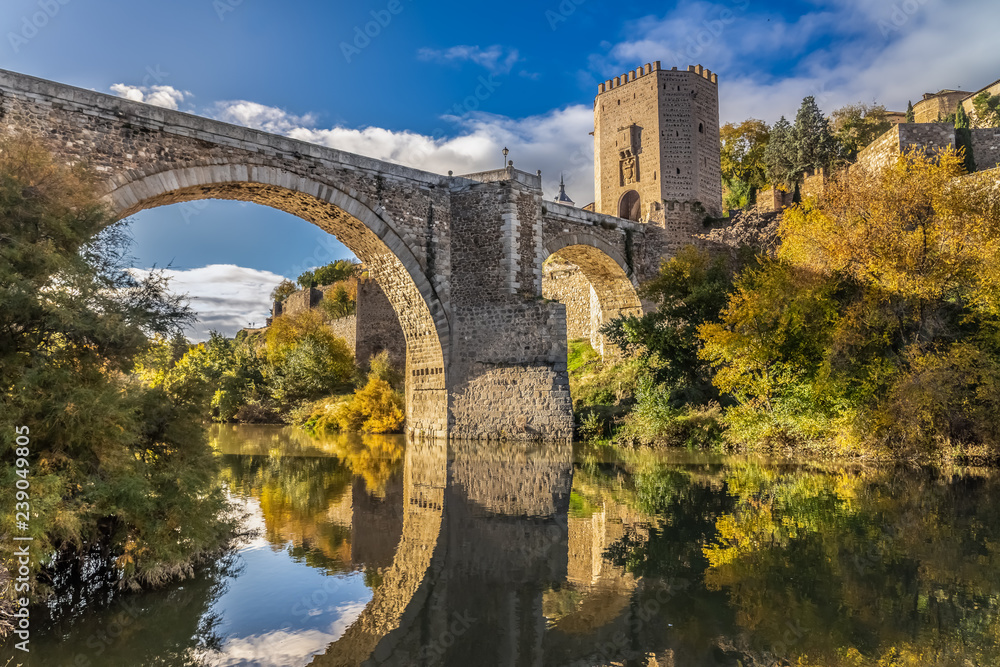The Puente de Alcantara, a Roman arch bridge in Toledo, Catile-La Mancha, Spain, spanning the Tagus River. The word comes from Arabic bridge - obrazy, fototapety, plakaty 