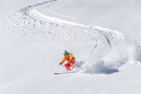 freeride skier skiing downhill through deep powder snow
