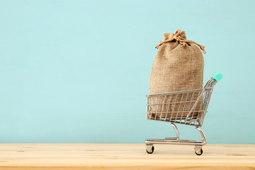 shopping cart with full bag full over blue wooden background.