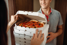 Delivery Man Shows Pizza To Customer At The Door