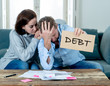 © SB Arts Media - Desperate young Couple showing debt sign having financial problems feeling stressed paying bills