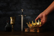 low key photo of king holding gold crown and sword. fantasy medieval period.