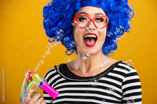 Cute girl wearing vibrant blue wig playing and blowing bubbles © Mat Hayward