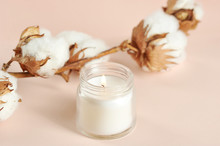 A Cotton Flower And A White Candle In A Glass Jar. Beige Background. Close-up. Macro Shooting.