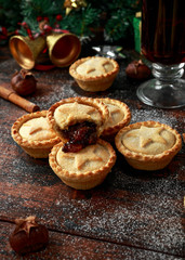 British Christmas mince pies with decoration, gifts, green tree branch on wooden rustic table