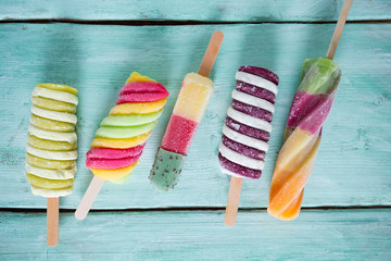 Wall Mural - colorful popsicle ice cream on turquoise wooden background