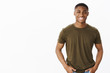 Nice african american guy smiling at camera while standing in casual pose in hucky t-shirt with hands in pockets looking friendly and self-assured making new friends, meeting coworker at new job