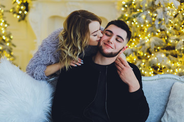 Wall Mural - Couple in love: a guy and a girl on the background of the Christmas tree. Christmas background 