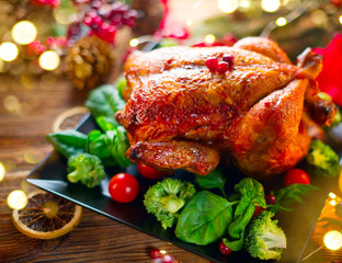 Wall Mural - Christmas family dinner. Roasted chicken on holiday served table, decorated with gifts and burning candles. Roasted turkey over wooden background