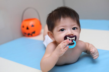 little kid baby sucking nipple pacifier teeth vampire dracula devil, costume of halloween celebration party