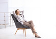 © New Africa - Beautiful young businesswoman relaxing in armchair indoors. Space for text