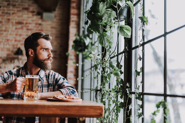 Handsome bearded man with drink spending time at pub