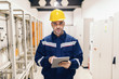 © dusanpetkovic1 - Portrait of young Caucasian man dressed in work wear using tablet while standing in heating plant.
