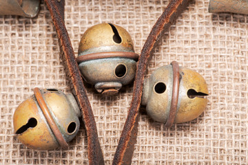 Antique vintage oxidize brass sleigh bells on leather strap and burlap background