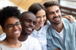 © fizkes - Happy multiethnic friends posing for photo together close up, excited smiling people making picture, colleagues, student in cafe embracing, having fun together, multiracial friendship concept