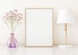 Home interior poster mock up with vertical frame on table, flowers in vase and lamp on warm white wall background. 3D rendering.