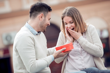 Wall Mural - Smiling man giving to his girlfriend a gift