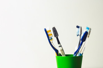 Wall Mural - Many toothbrushes in a plastic cup on a white background. The concept of changing toothbrushes, oral hygiene, dentistry, a large and friendly family