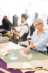 Wall Mural - Side view portrait of adult woman sewing clothes and making patterns while working in atelier workshop