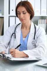 Wall Mural - Doctor woman at work. Physician filling up medical history records form at the desk. Medicine, healthcare  concept