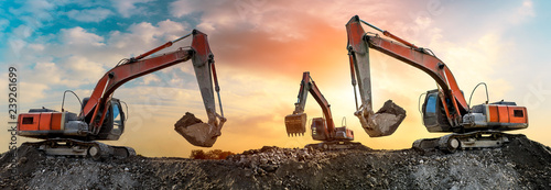 Fotografía Three excavators work on construction site at sunset,panoramic view