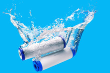New Carbon Filter Cartridge For House Water Filtration System Isolated On Blue Background. Splash. Concept.