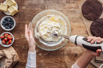 Wall Mural - partial top view of woman mixing cream for delicious homemade cake