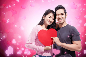 Poster - Romantic asian couple in love standing together and holding red heart shape