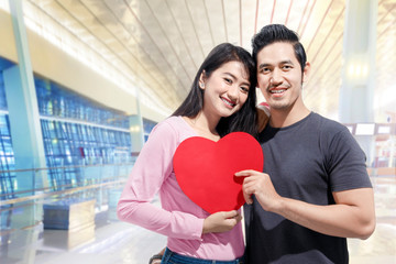 Poster - Romantic asian couple in love standing together and holding red heart shape