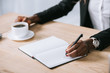© LIGHTFIELD STUDIOS - cropped view of african american woman with notebook and cup of coffee