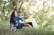 © soleg - young couple sitting on the grass in the forest and looking on sunset, summer nature, bright sunlight, shadows and green leaves, romantic feelings