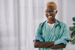 © LIGHTFIELD STUDIOS - smiling african american nurse in gloves standing with crossed arms while looking at camera