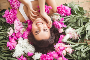 Young beautiful woman holding flowers. Attractive girl with peony pink. Beauty portrait. Female close up portrait