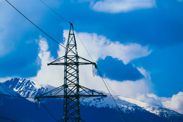 Sticker - High-voltage powerful electricity tower with wires, alpine ice mountains peaks  on background.