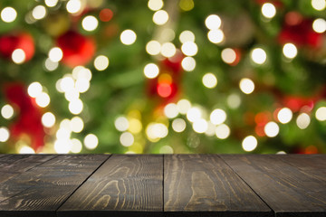 wooden dark tabletop and blurred christmas tree bokeh. xmas background for display your products.