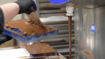 Wall Mural - production, cooking and people concept - confectioner filling candy mold with chocolate at confectionery shop