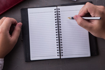 Top view of man hands writing on empty notebook with pen in office. Businessman working at office desk. Business concept.