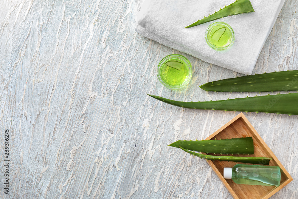 Bowls with gel and aloe leaves on white wooden table