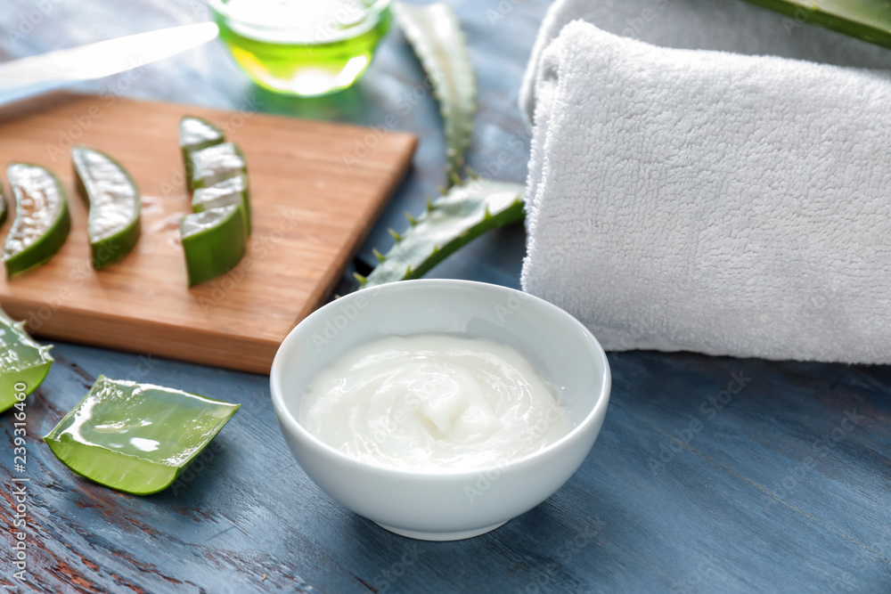 Bowl with healing cream and aloe on wooden table
