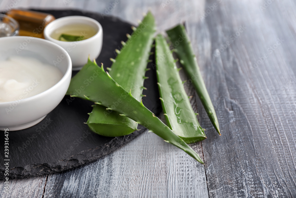 Fresh leaves with cosmetic products on wooden table