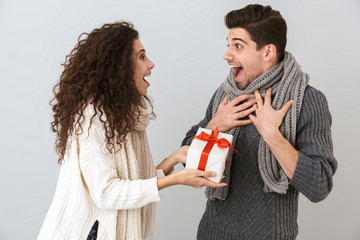 Sticker - Image of surprised man and woman rejoicing while standing with present box, isolated over gray background