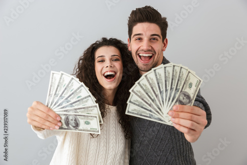 Fotografie, Obraz Image of rich man and woman holding fan of dollar money, isolated over gray back