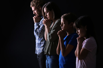 Praying family on dark background