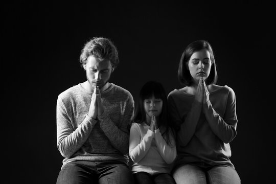 Praying family on dark background