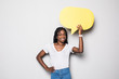 © F8  \ Suport Ukraine - Portrait of a happy young african woman holding empty speech bubble isolated over gray background