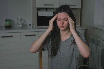 Woman with headache in the kitchen at night. Insomnia and depression.