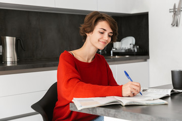 Wall Mural - Smiling young woman studying at the table