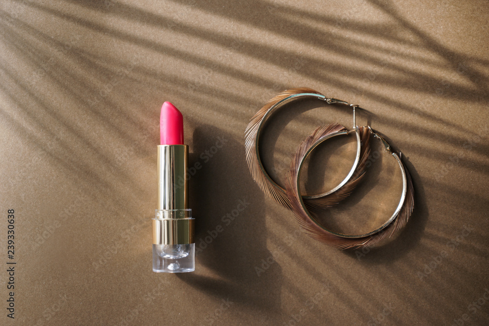 Pink lipstick with earrings on color background